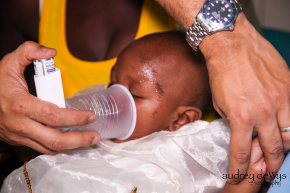 A baby who is having trouble breathing is treated with a bronchodilator and a makeshift aerochamber to help distribute the medication.
